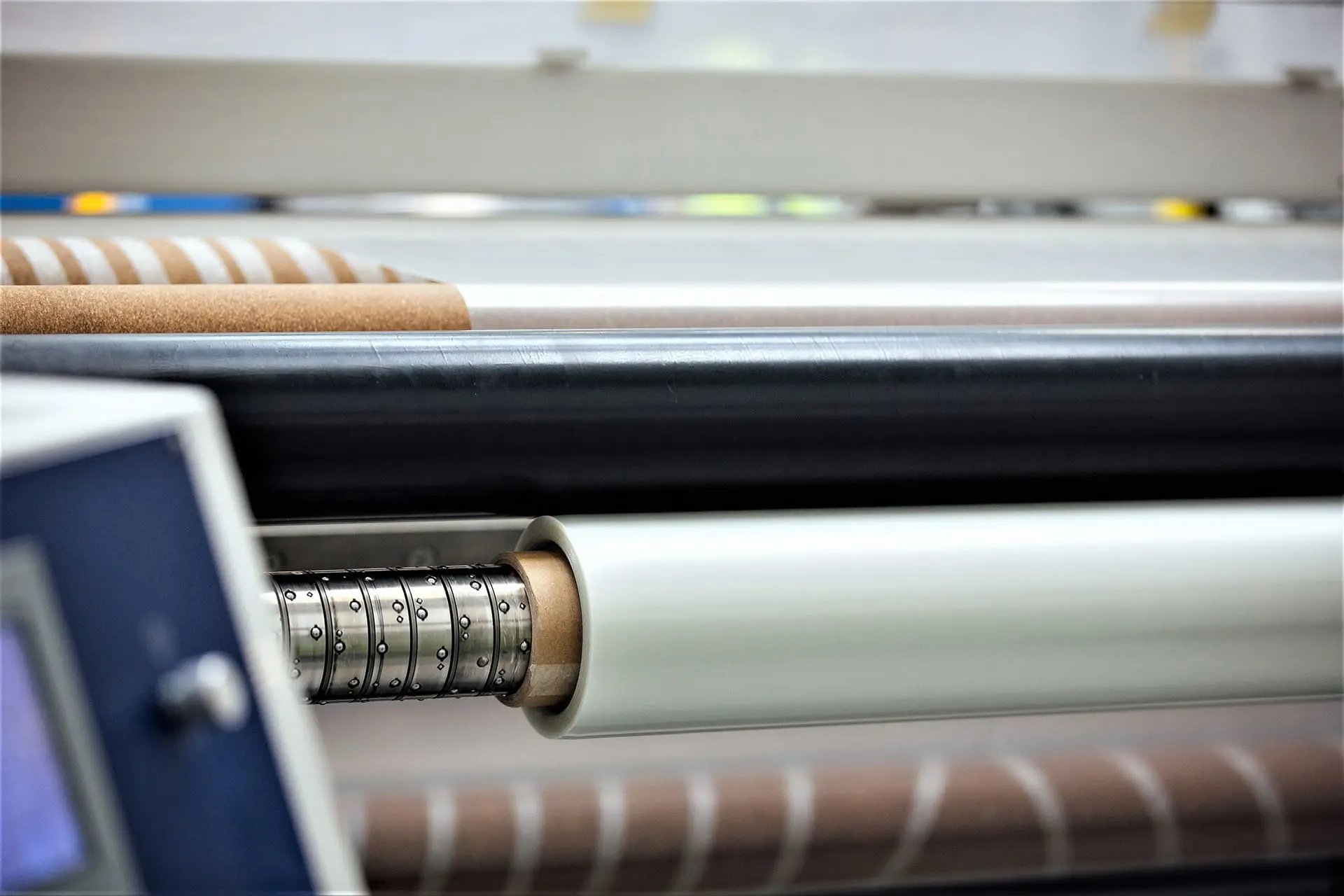 Roll-Slitting-Retouched Close-up of a paper or film roll winding on an industrial machine with visible rollers.