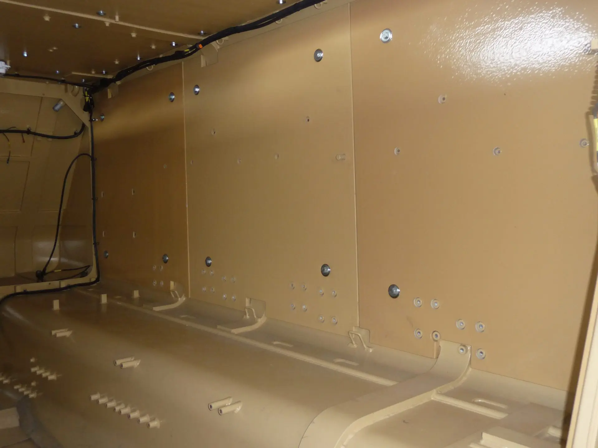 Spall-Liner Tan metal interior with bolts and wiring, featuring a curved floor and flat vertical panels.