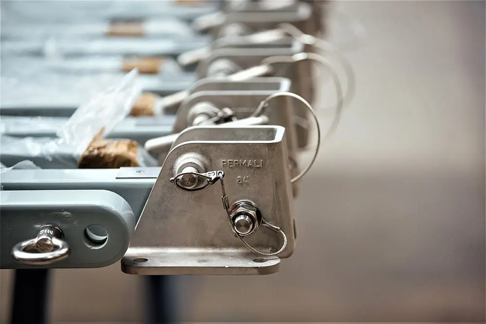Stanchions-Retouched Close-up of metal industrial brackets with locking pins, labeled PERMALI, arranged in a row.