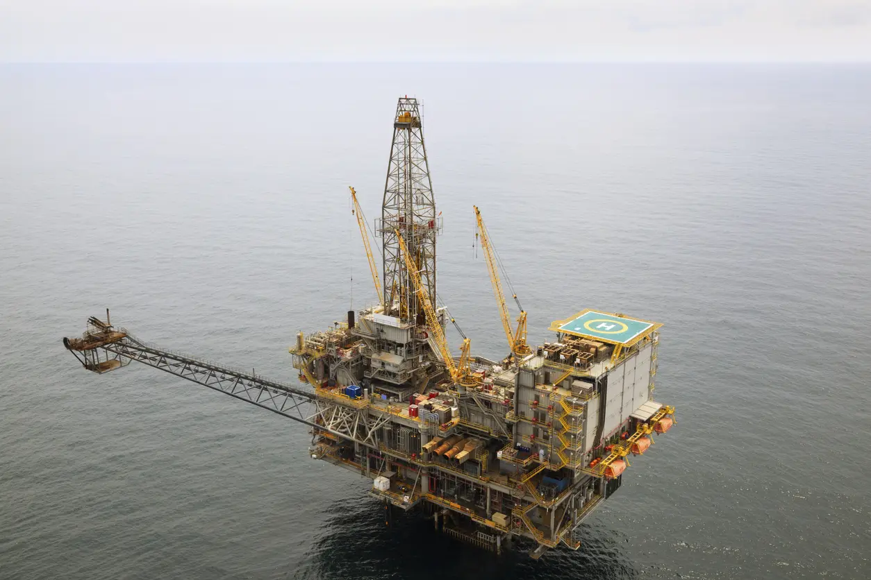 Oil Rig Offshore oil drilling platform with a helicopter landing pad, surrounded by calm ocean water.