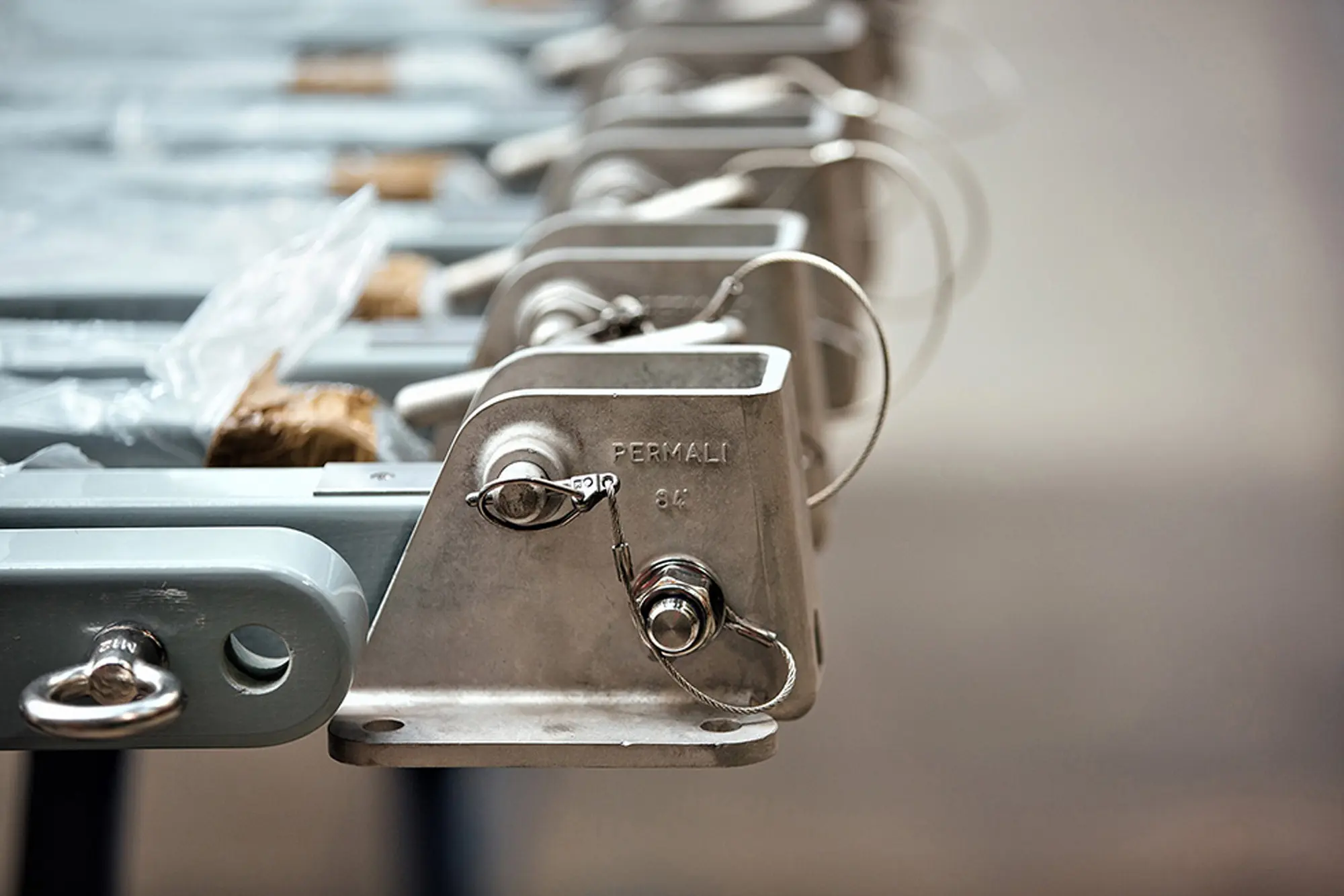 BESPOKE Close-up of metal industrial brackets with safety pins attached, mounted in a row.
