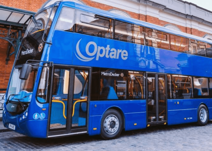 A blue double-decker Optare MetroDecker bus parked on a cobblestone street near a brick building.