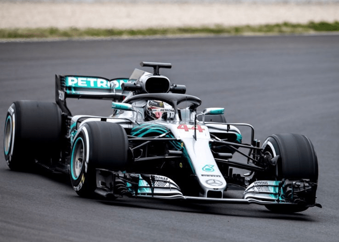 A Mercedes Formula 1 car races on a track, featuring the number 44 and Petronas branding.
