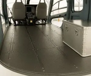 Interior of a helicopter cargo area with two seats and a metal storage box on the floor.