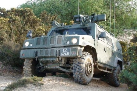 panther1-800x600 A green armored military vehicle with large tires on a dirt path surrounded by bushes and trees.