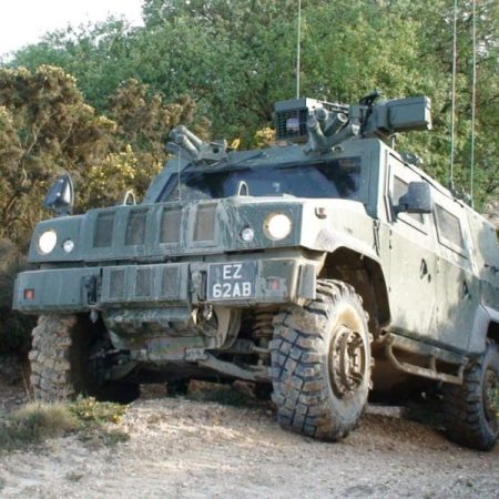 panther1-800x600 A green armored military vehicle with large tires on a dirt path surrounded by bushes and trees.