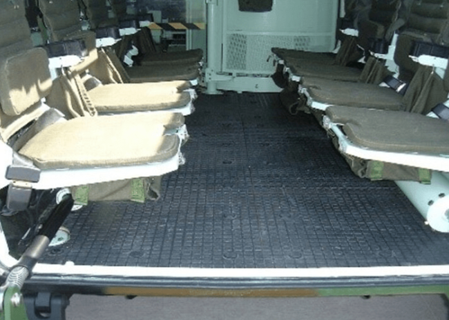 1.png-1 Interior of a military vehicle with two rows of foldable seats facing each other.