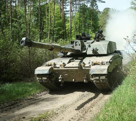 permali battlejacket fuel tank protection coating A military tank moving on a dirt road through a forest, with smoke visible behind it.