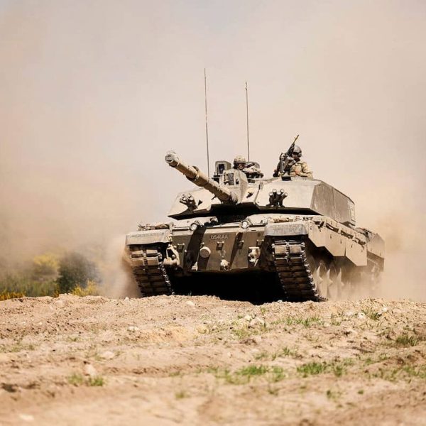 supporting defence on every front tank A military tank moves through a dusty field, raising clouds of dirt under a clear sky.