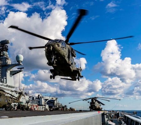 Two military helicopters take off from a naval ship, showcasing air defence composites.